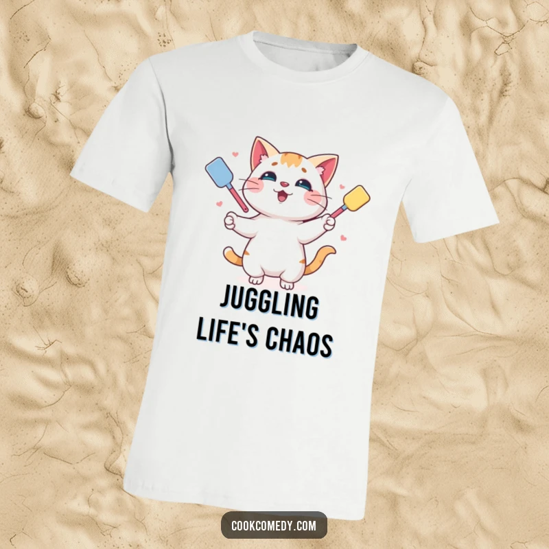 Funny t-shirt showcasing a playful cat skillfully juggling multiple colorful spatulas, perfect for kitchen antics.